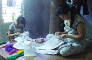 Vợ, con anh Nguyễn Văn Đại ở tổ 12, phường Thịnh Lang (TPHB) phải tìm việc thêu thuê để giảm bớt khó khăn.
