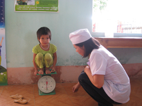 Cán bộ Trạm y tế xã Đồng Tâm (huyện lạc Thuỷ) cân, đo cho trẻ em dưới 6 tuổi.