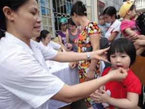 Cán bộ Trạm y tế phường Hữu Nghị (TPHB) cho trẻ uống vitamin A.