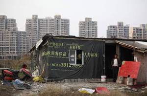 Một người dân nhập cư đứng bên căn nhà tạm bợ của mình ở Thượng Hải - Ảnh: Reuters
