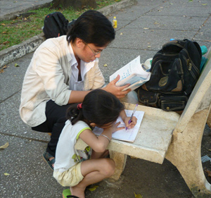 Phạm Minh Khiết đang dạy học cho bé Bồng tại Công viên 30.4.
