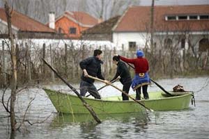 Người dân trong làng Obot, gần thành phố Shkodra, Albani chèo thuyền trong nước lũ vào ngày 10/1. Các nhà khoa học cảnh báo lũ lụt và hạn hán sẽ tăng khi trái đất ấm lên. Ảnh: AP.