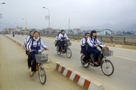 Học sinh đi xe đạp điện không đội mũ bảo hiểm. (Ảnh chụp trên cầu Hòa Bình, thành phố Hòa Bình)