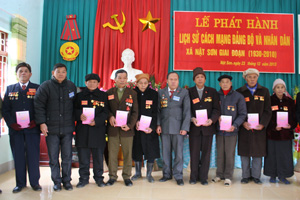 Đồng chí Bùi Văn Sáng, Bí thư Đảng ủy xã trao cuốn lịch sử Đảng bộ cho các đồng chí lão thành cách mạng.