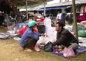 “Thầy thuốc”  (ngồi bên phải) giới thiệu là người Chăm, quê ở Ninh Thuận đang chẩn đoán và kê đơn thuốc cho một người bệnh tại chợ Lỗ Sơn.