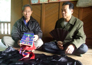 Nghệ nhân Mo Bùi Văn Lựng, xóm Lầm, xã Phong Phú, huyện Tân Lạc (bên phải) chuẩn bị lễ phục cho lễ hội Khai hạ Mường Bi năm 2015.