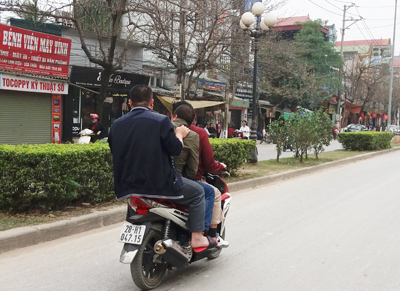 Xe máy chở 3 người không đội mũ bải hiểm. Ảnh chụp trên đường Chi Lăng (thành phố Hòa Bình).