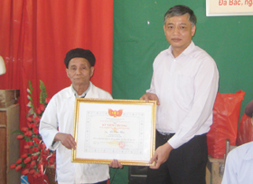 Đồng chí Doãn Mậu Diệp - Phó Bí thư Tỉnh ủy trao kỷ niệm chương vì sự nghiệp đại đoàn kết dân tộc cho trưởng bản Lê Văn Hìn.