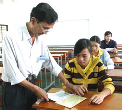 Giám thị đối chiếu giấy tờ liên quan với phiếu dự thi của thí sinh trong kỳ thi tuyển sinh ĐH-CĐ 2009.