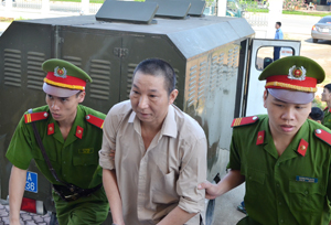 Hung thủ Lê Văn Minh được dẫn giải vào hội trường xét xử. 
