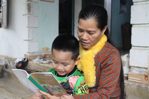 Chị Nguyễn Thị Đông tranh thủ lúc rảnh rỗi dạy cháu ngoại học bài.