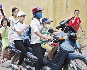 Nhiều trẻ em ngồi trên xe máy không đội mũ bảo hiểm khi tham gia giao thông.