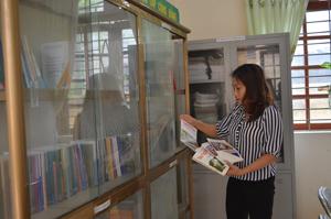 Cán bộ Trung tâm Học tập cộng đồng xã Thanh Nông tìm kiếm tài liệu về truyền thống hiếu học và tinh thần hăng hái diệt giặc dốt của người dân địa phương trong những năm đầu cả nước thi đua chống nạn mù chữ.