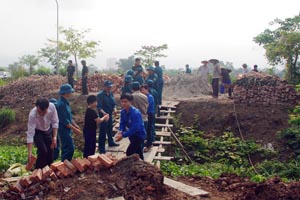 Lực lượng dân quân, ĐVTN và nhân dân giúp gia đình ông Đoàn Văn Phụng vận chuyển vật liệu, đào móng xây dựng nhà.

