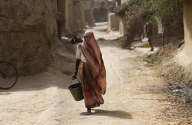 Một phụ nữ Ấn Độ xách xô đi lấy nước trong một ngày nắng nóng ở ngoại ô thành phố Amritsar, bang Punjab.
