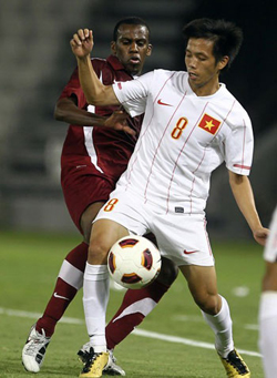 Một pha bóng trong trận lượt đi giữa Việt Nam (áo trắng) và Qatar.