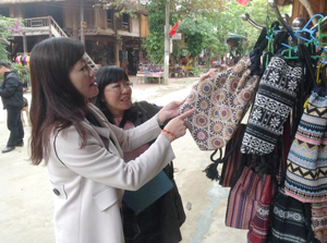 Khách du lịch thích thú lựa chọn mặt hàng thổ cẩm truyền thống - sản phẩm của người dân bản Lác, xã Chiềng Châu (Mai Châu).