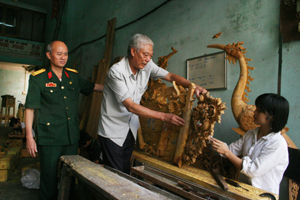 CCB Đào Ngọc Phúc hướng dẫn tỉ mỉ công việc cho thợ học việc tại xưởng mộc của gia đình.