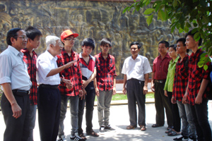 Thầy Nguyễn Bạch Đằng trò chuyện cùng lãnh đạo,  giáo viên, học sinh bên bức phù điêu truyền thống của nhà trường.