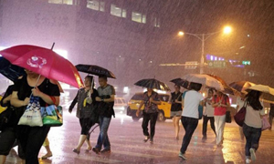 Người dân tại Đài Bắc, Đài Loan (Trung Quốc) đang đi bộ dưới cơn mưa lớn do siêu bão Soudelor gây ra. (Ảnh: EPA)