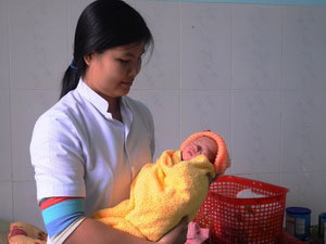 Chị Hồ Thị Hiếu cán bộ y tế của trạm y tế xã Trà Cang và bé trai Hồ Quốc Khánh.